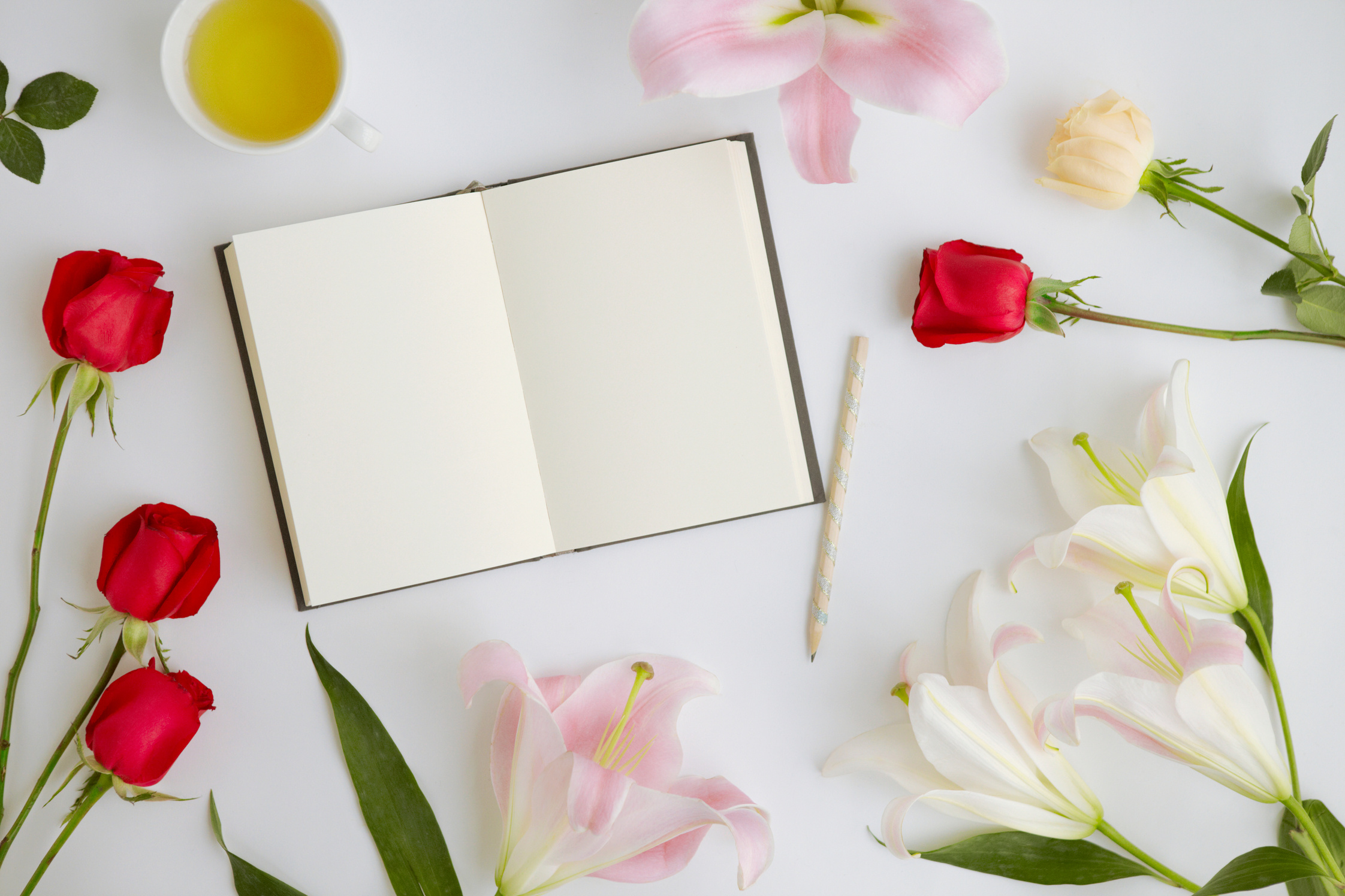 Flatlay of white background with flowers and journal